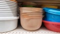 Multi-colored plastic containers of different shapes and sizes with and without lids, stacked in a pile on a store window. Sale of Royalty Free Stock Photo