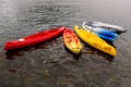 Multi-colored plastic kayaks are on the pier near the shore