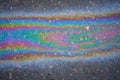 Multi-colored poisonous spots of spilled gasoline on wet pavement during rain. Royalty Free Stock Photo