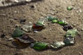 Multi-colored sea glasses are laid out on the sandy shore in the form of a heart near the sea with waves. Background. Love concept Royalty Free Stock Photo