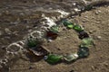 Multi-colored sea glasses are laid out on the sandy shore in the form of a heart near the sea with waves. Background. Love concept Royalty Free Stock Photo