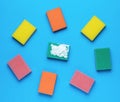 Multi-colored set of bright foam sponges on a blue background. Minimal concept of washing and cleaning Royalty Free Stock Photo