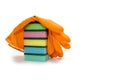 Multi-colored sponges for washing and cleaning stacked and covered with an orange glove on a white background