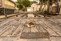 A multi-colored street cat lies resting on the street on a wooden flooring on the street in sunny weather. Horizontal plan. Copy