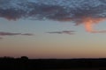 Wispy sunset clouds over a darkened skyline