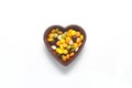 multi-colored sweet candies in heart shaped bowl on white background, top view. Space for text Royalty Free Stock Photo