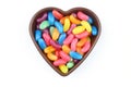 multi-colored sweet candies in heart shaped bowl on white background, top view. Space for text Royalty Free Stock Photo