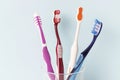 Multi-colored toothbrushes in a glass cup, blue background Royalty Free Stock Photo