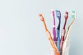 Multi-colored toothbrushes in a glass cup, blue background Royalty Free Stock Photo