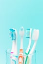 Multi-colored toothbrushes in a glass cup on blue background Royalty Free Stock Photo
