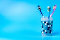 Multi-colored toothbrushes in a plastic cup isolated on a blue background Royalty Free Stock Photo