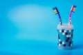 Multi-colored toothbrushes in a plastic cup isolated on a blue background Royalty Free Stock Photo