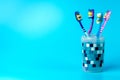 Multi-colored toothbrushes in a plastic cup isolated on a blue background Royalty Free Stock Photo