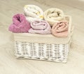 Multi-colored towels rolled into rolls in a white wicker basket on the floor Royalty Free Stock Photo