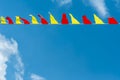 Multi colored triangular flags develop on the background of blue sky. Colorful fairground flags