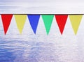 Multi Colored Triangular Flags Hanging against the backdrop of blue river.