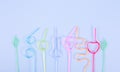 Multi-colored tubes for cocktails lie in a row on a purple background. Multi-colored straws for drinks twisted in different Royalty Free Stock Photo