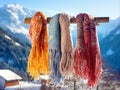 Multi-colored warm scarves hang on a wooden pole against the backdrop