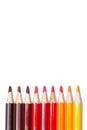 Multi-colored wooden pencils in red shades on a white isolated background, autumn colors, mock up, vertically