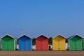 Five multi-coloured beach huts under a blue sky Royalty Free Stock Photo