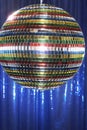 Multi-coloured disco ball in front of blue stage curtain close up Royalty Free Stock Photo