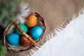 Multi coloured Easter eggs in wicker basket on rustic background Royalty Free Stock Photo