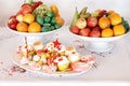 Multi coloured fruit and cupcakes on white plates on the table