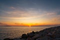 Multi-coloured twilight sky above vast water surface. Sun rising behind mainland and Adriatic sea. Romantic scene