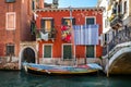 Multi coloured yacht moored on canal with hanging laundry in Venice, Italy