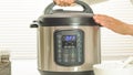 Multi cooker close up on kitchen table. Woman lifting the lid.