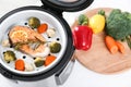 Multi cooker with salmon steak and garnish on white table Royalty Free Stock Photo