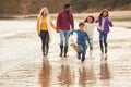 Multi-Cultural Family With Pet Dog Walking Along Beach Shoreline On Winter Vacation Royalty Free Stock Photo