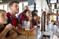 Multi-Cultural Group Of Friends Wearing Team Shirts In Sports Bar Celebrating Watching Game On TV Royalty Free Stock Photo