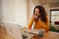 Multi-cultural Young professional blowing nose while taking business call. Remote working female sick at home