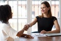 Multiethnic businesswomen greeting each other shaking hands starting business negotiations