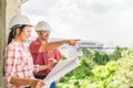 Multi-ethnic couple of construction engineers working together with blueprint at building site