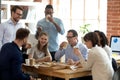 Multi-ethnic employees group enjoy takeaway food friendly conversation in office