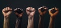 Multi ethnic fists raised up in sign of protest and social unrest, cut out, isolated on black background.