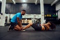 Mixed race friends doing cross fit in the gym. African American male encouraging African American female during sit-ups Royalty Free Stock Photo