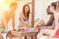 Multi ethnic friends enjoying a sunny day on the beach - Young people talking and drinking cocktail under beach umbrella - Royalty Free Stock Photo