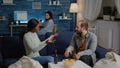 Multi-ethnic friends relaxing on couch while giving high five laughing and having fun