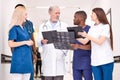 multi-ethnic group of doctors talking in hospital hallway examining x-ray scans together Royalty Free Stock Photo