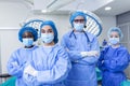 Multi-ethnic group of four healthcare workers, a team of doctors, surgeons and nurses, performing surgery on a patient in a Royalty Free Stock Photo