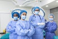Multi-ethnic group of four healthcare workers, a team of doctors, surgeons and nurses, performing surgery on a patient in a Royalty Free Stock Photo