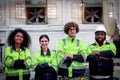 Multi-ethnic group of four industrial women men staff worker team wearing safety vest, standing with arms crossed at CNC