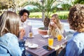 Multi-ethnic group of friends having a drink together in an outdoor bar. Royalty Free Stock Photo