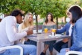 Multi-ethnic group of friends having a drink together in an outdoor bar. Royalty Free Stock Photo