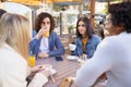 Multi-ethnic group of friends having a drink together in an outdoor bar. Royalty Free Stock Photo