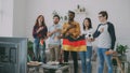 Multi-ethnic group of friends listening and singing German national anthem before watching sports championship on TV Royalty Free Stock Photo