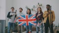 Multi ethnic group of friends listening and singing British national anthem before watching sports championship on TV Royalty Free Stock Photo